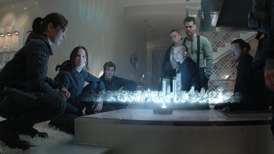 main characters of Hunger Games discussing of their strategy in front of an holographic map